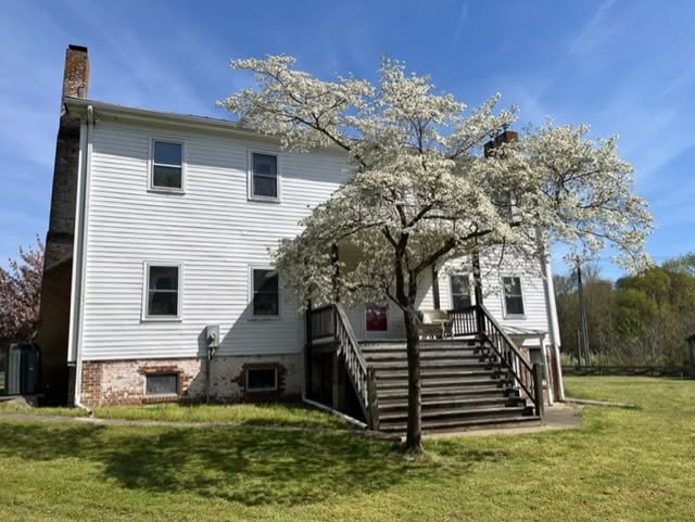 Historic Meadow Hill house with white siding, brick chimney, and a flowering tree